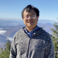 Photo of Yuezhi Mao standing in front of mountains